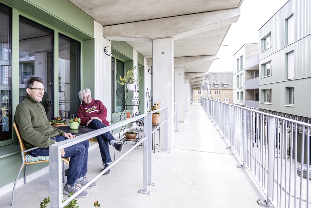 Zwei Personen, die auf einer Terrasse sitzen und lachen.