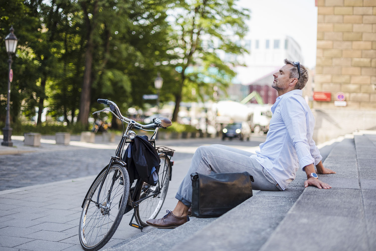 Mann entspannt auf Steintreppe, Fahrrad steht vor ihm