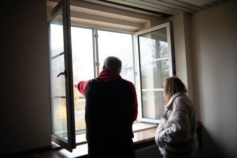 Ein Mann und eine Frau stehen an einem Fenster und schauen heraus. Er zeigt auf etwas