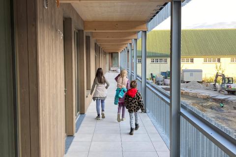 Drei Mädchen laufen einen Laubengang entlang